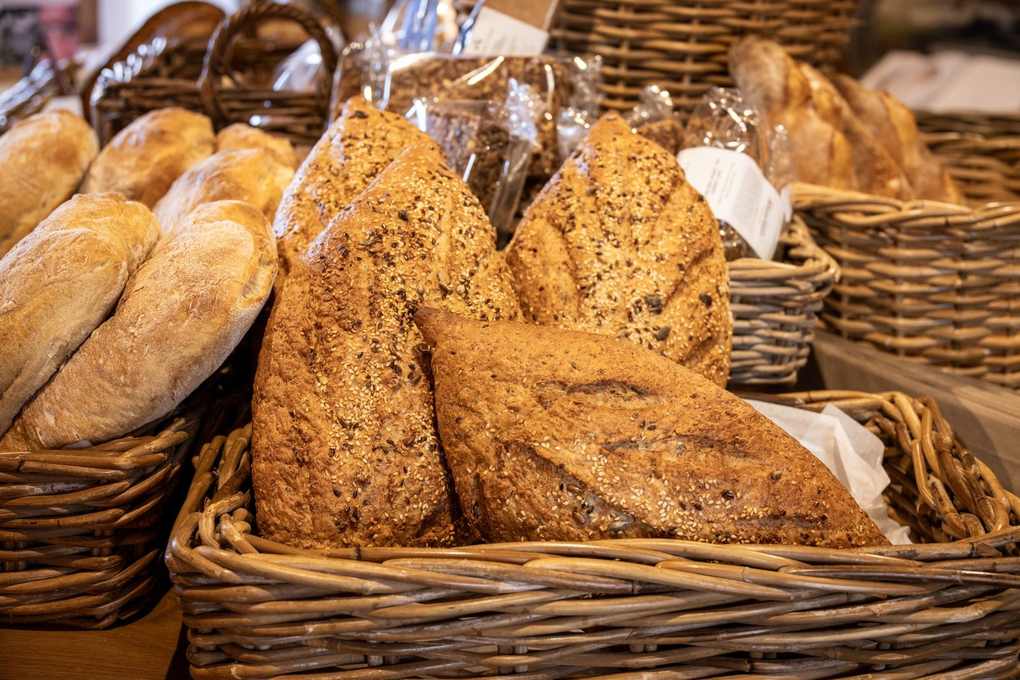 Paniers de pain artisanal sur une table, différents types de baguettes et pains ronds