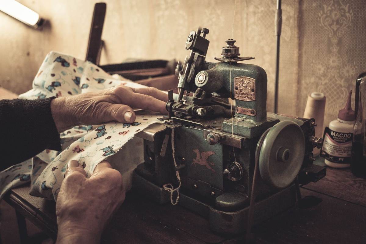 Mains guidant un tissu sur une vieille machine à coudre verte