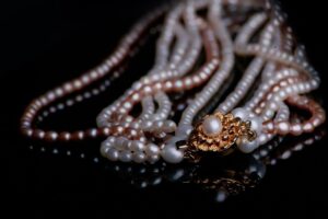 Collier de perles blanches et rosées avec fermoir or sur fond noir